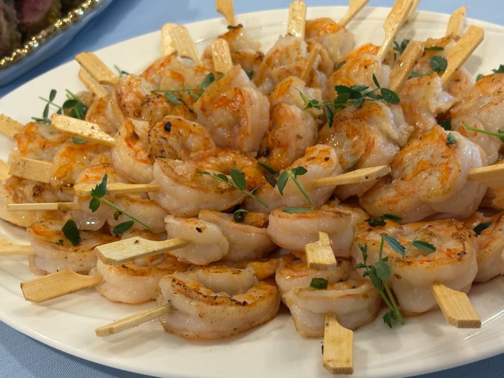 Chili shrimp skewers arranged on a white platter
