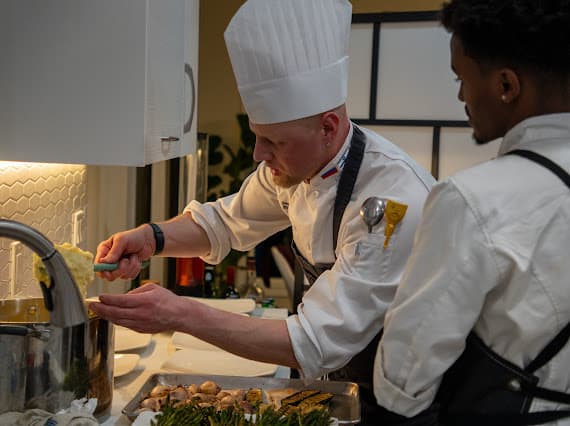 Chef Sergei preparing food in the kitchen with an assistant