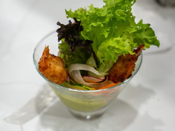 A plated shrimp salad with fresh greens in a glass bowl