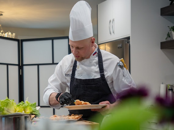 Chef Sergei Didenko plating a dish during Tatiana's private dinner